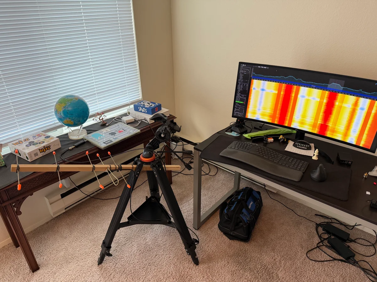 The antenna beside a desk with SDR software displaying a radio spectrum and waterfall on the monitor